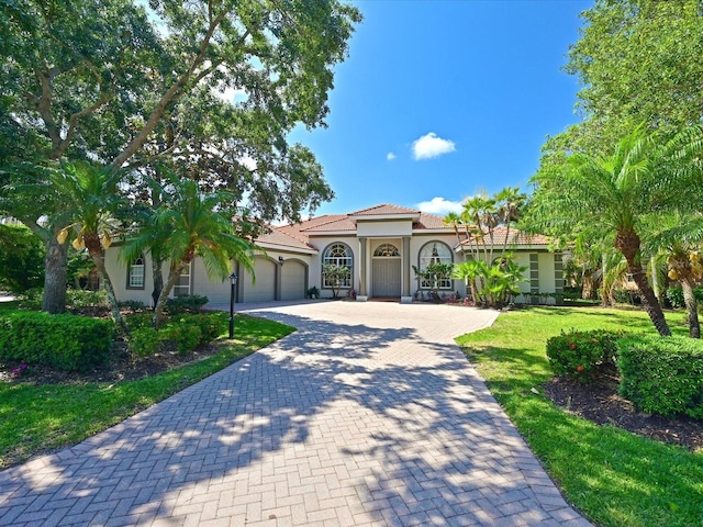 mediterranean / spanish house featuring a garage and a front lawn