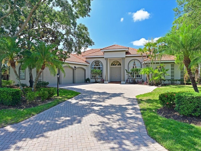 mediterranean / spanish-style house featuring a garage and a front yard