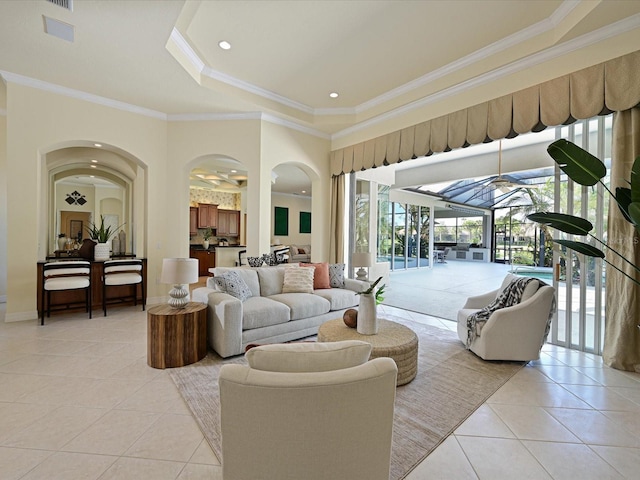 living room with light tile patterned floors, crown molding, and a tray ceiling