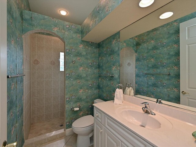 bathroom with tile patterned flooring, vanity, toilet, and a tile shower