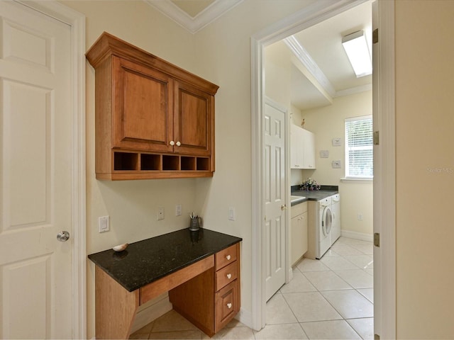 kitchen with dark stone counters, light tile patterned floors, washing machine and clothes dryer, and crown molding