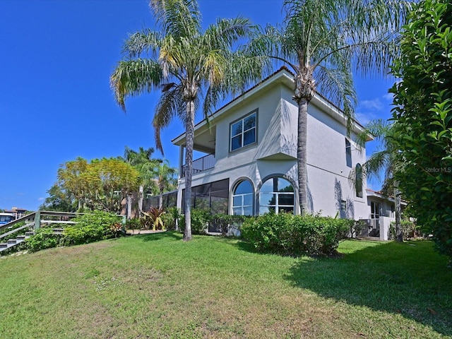 view of home's exterior with a balcony and a yard