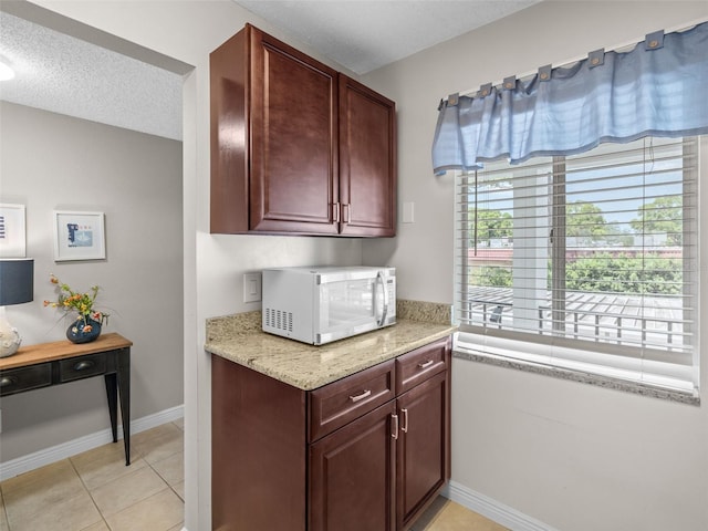 kitchen featuring a textured ceiling, light tile floors, and light stone countertops