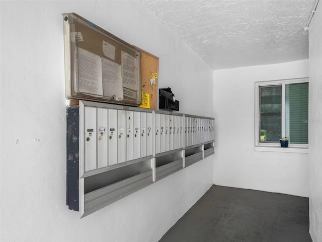 interior space featuring concrete floors, a textured ceiling, and mail boxes