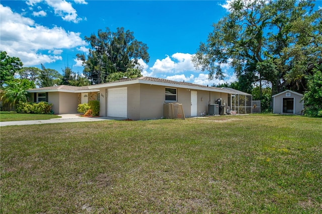 ranch-style home featuring a front lawn, a garage, and central air condition unit