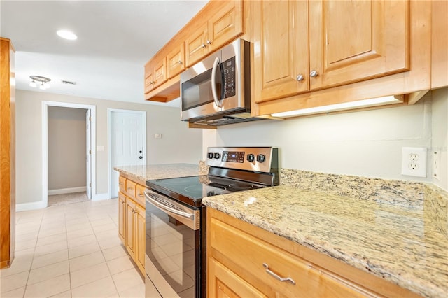 kitchen featuring light brown cabinets, stainless steel appliances, light tile floors, and light stone countertops