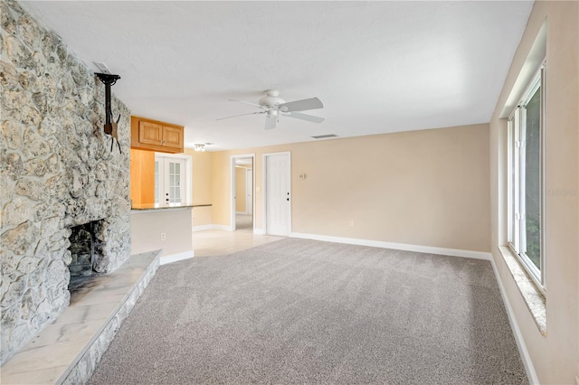 unfurnished living room with light colored carpet, a fireplace, and ceiling fan