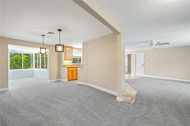 unfurnished living room featuring carpet flooring and ceiling fan