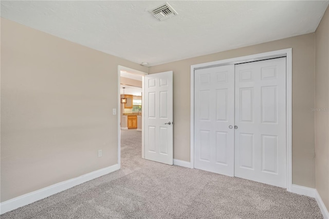 unfurnished bedroom with light colored carpet and a closet