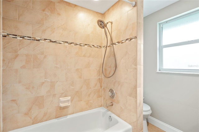 bathroom featuring tiled shower / bath, a healthy amount of sunlight, and toilet