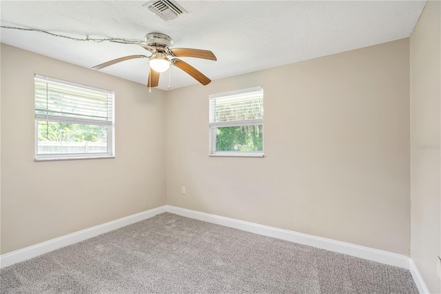 carpeted spare room featuring a wealth of natural light and ceiling fan