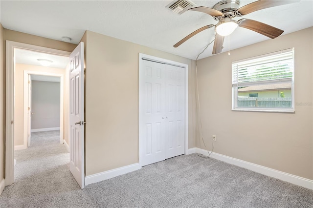 unfurnished bedroom with light colored carpet, a closet, and ceiling fan