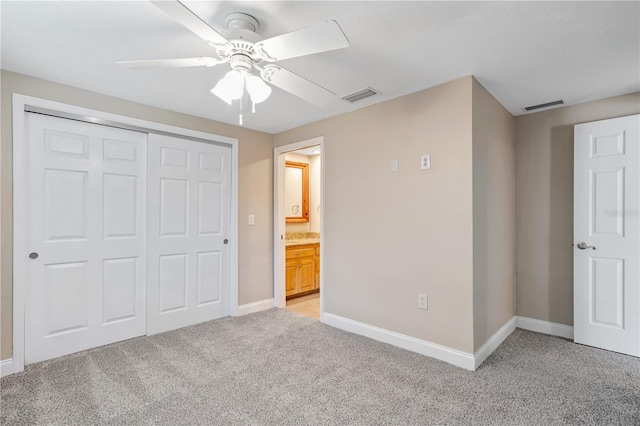 unfurnished bedroom featuring light colored carpet, connected bathroom, ceiling fan, and a closet