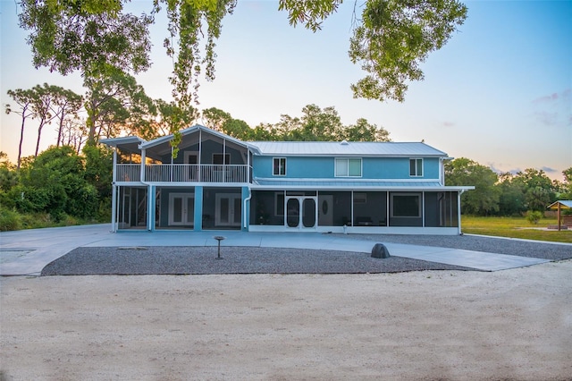 back house at dusk with a sunroom