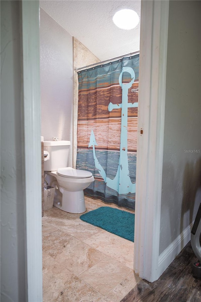 bathroom with a textured ceiling, tile floors, and toilet