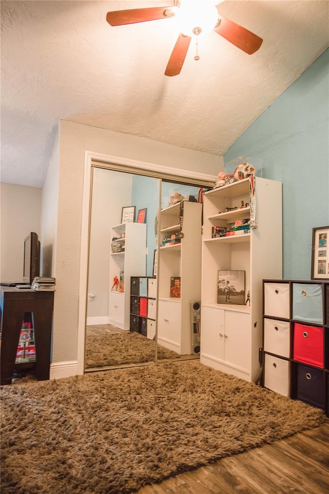 bedroom featuring ceiling fan, lofted ceiling, a textured ceiling, a closet, and hardwood / wood-style floors