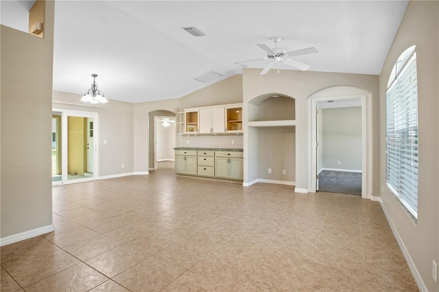 unfurnished living room featuring ceiling fan with notable chandelier, light tile patterned floors, and vaulted ceiling