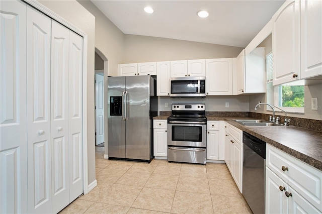 kitchen with stainless steel appliances, white cabinets, sink, lofted ceiling, and light tile patterned floors