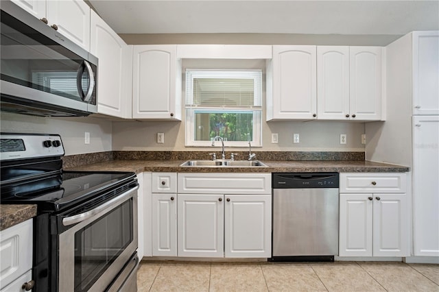 kitchen with sink, appliances with stainless steel finishes, light tile patterned floors, and white cabinetry