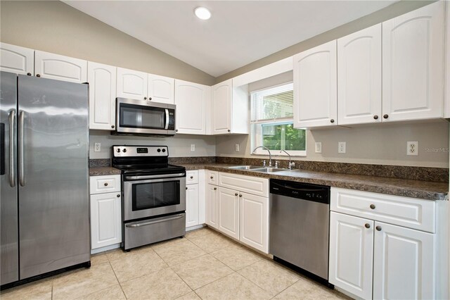 kitchen with light tile patterned floors, white cabinets, stainless steel appliances, vaulted ceiling, and sink