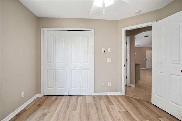 unfurnished bedroom with light hardwood / wood-style flooring, a closet, and ceiling fan