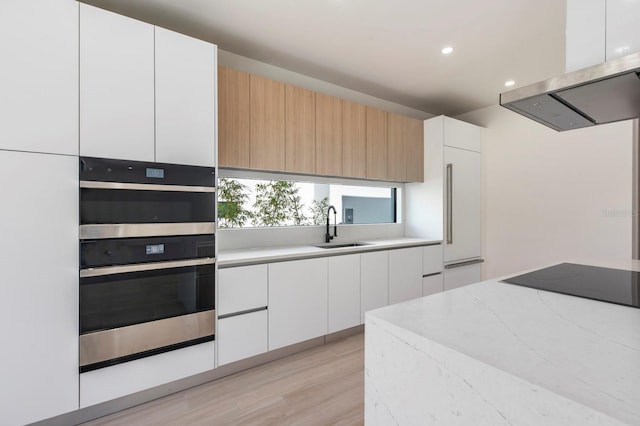 kitchen featuring light hardwood / wood-style flooring, double oven, white cabinetry, extractor fan, and sink