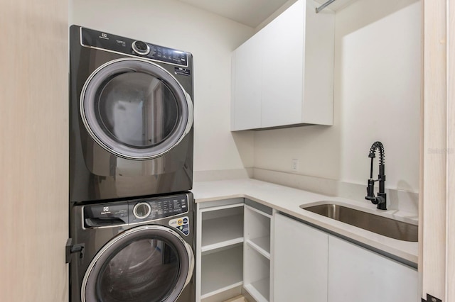 laundry room with cabinets, stacked washer / dryer, and sink