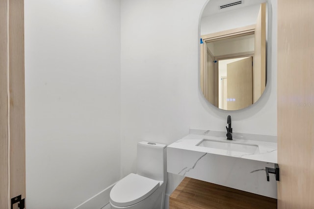 bathroom with wood-type flooring, toilet, and sink