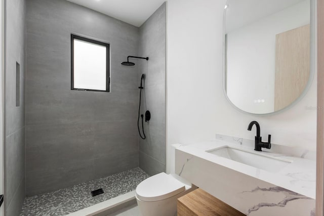 bathroom with tiled shower, toilet, and sink