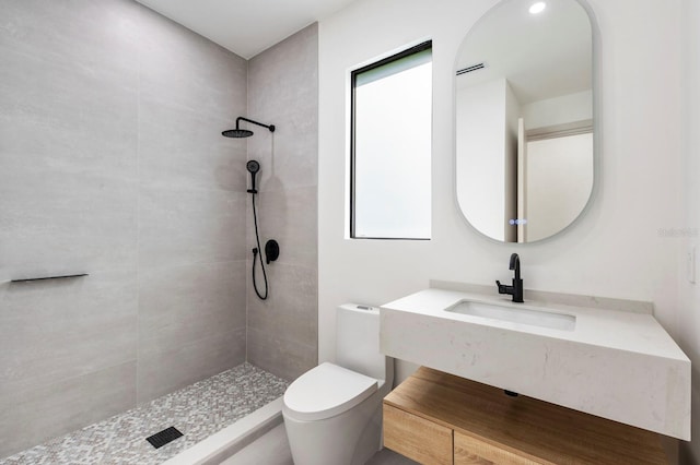 bathroom with sink, toilet, and a tile shower