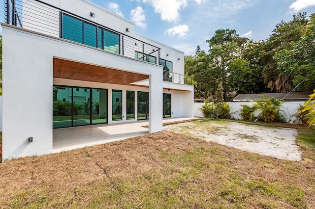 back of property with a patio, a balcony, and a lawn