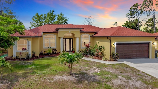 mediterranean / spanish house featuring a garage and a lawn