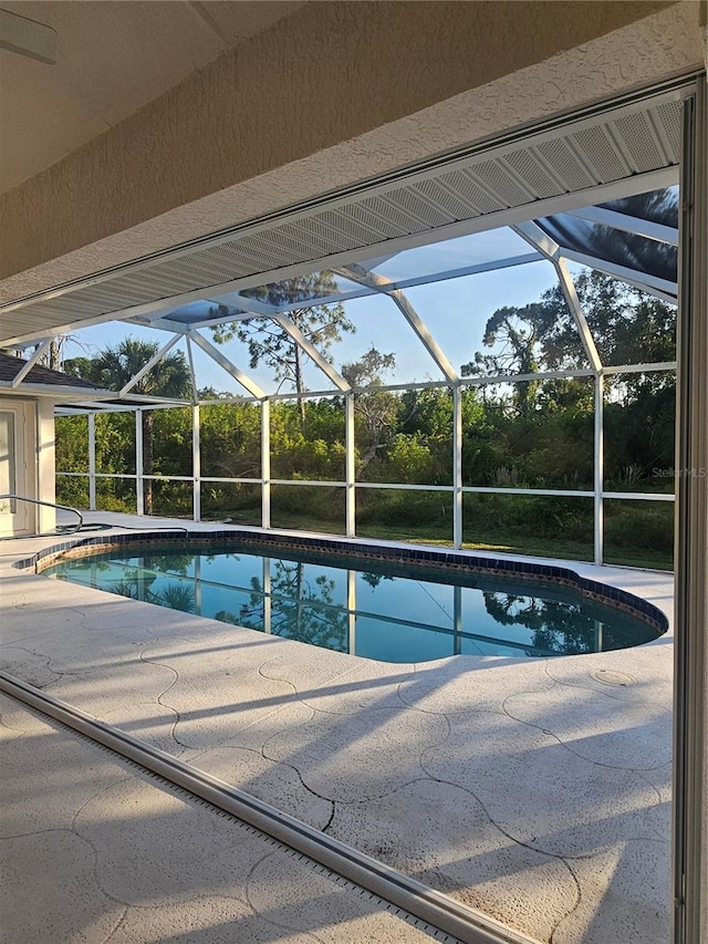 view of pool featuring glass enclosure and a patio area