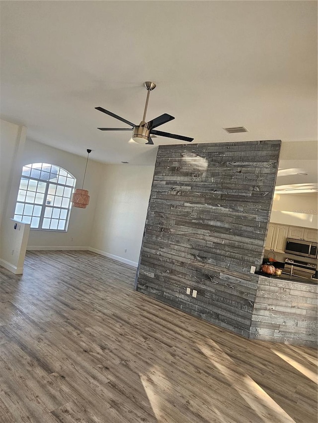 unfurnished living room featuring ceiling fan and hardwood / wood-style floors