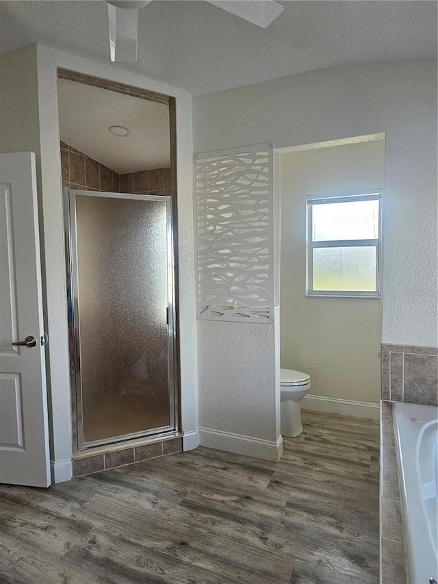 bathroom with hardwood / wood-style floors, shower with separate bathtub, toilet, and a textured ceiling