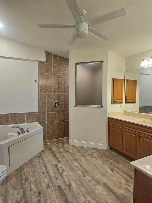 bathroom with a tub, vanity, ceiling fan, wood-type flooring, and toilet