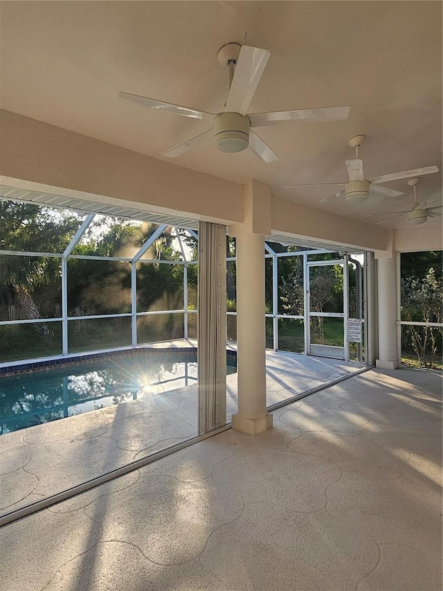 view of pool featuring glass enclosure, ceiling fan, and a patio