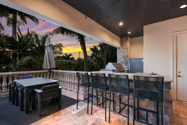 patio terrace at dusk with a grill and a bar