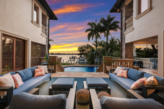 patio terrace at dusk with a water view, a fenced in pool, pool water feature, and an outdoor hangout area