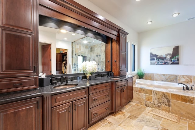 bathroom featuring tile flooring, a healthy amount of sunlight, tiled bath, and dual bowl vanity