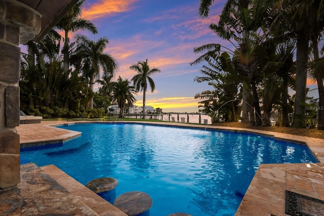 pool at dusk featuring pool water feature