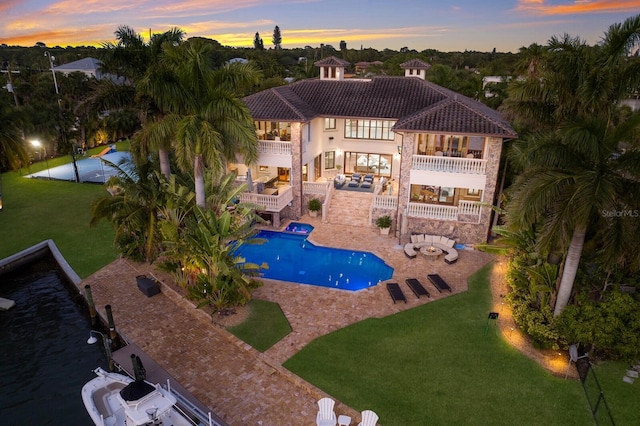 pool at dusk with a lawn and a patio area