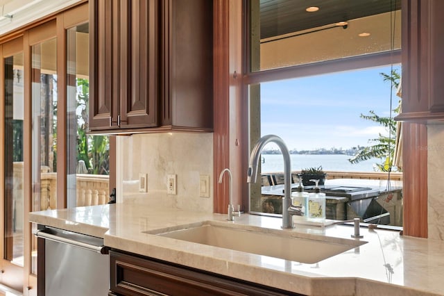 kitchen with dishwasher, a water view, sink, and backsplash