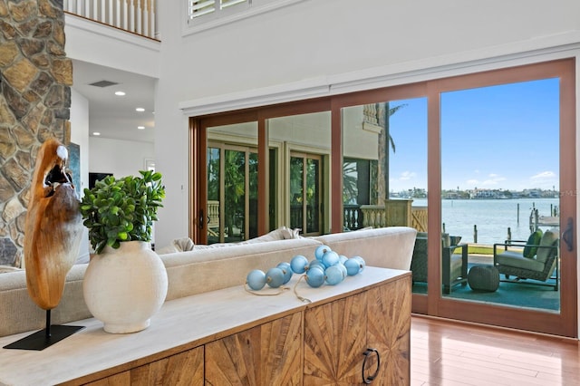 living room with a water view, a towering ceiling, and light wood-type flooring