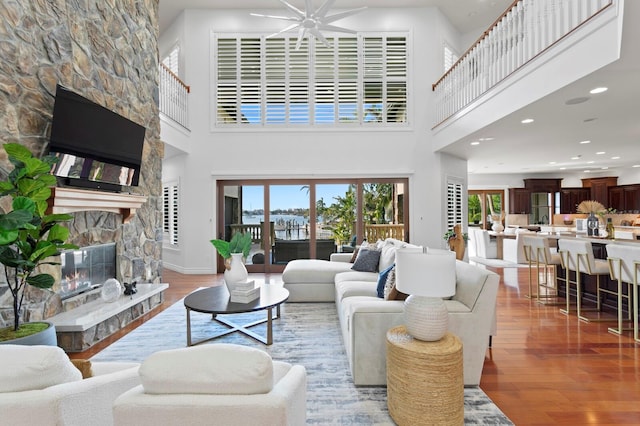 living room featuring a stone fireplace, hardwood / wood-style floors, and a high ceiling