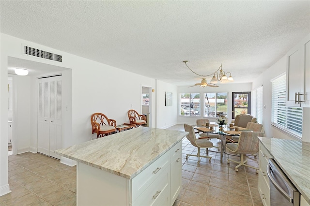 kitchen featuring dishwasher, white cabinetry, light tile floors, and a kitchen island