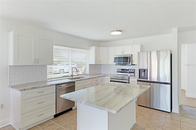 kitchen featuring a center island, appliances with stainless steel finishes, backsplash, sink, and light tile floors