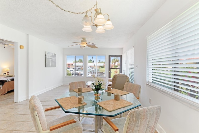 tiled dining room featuring ceiling fan with notable chandelier and a textured ceiling