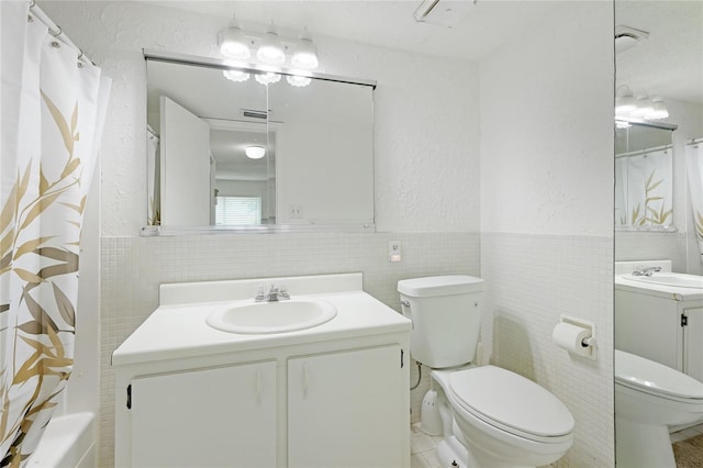 bathroom with a textured ceiling, tile walls, backsplash, vanity, and toilet