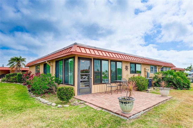 back of house with a lawn, central AC unit, and a patio area